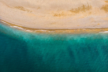 Aerial top down view of clear sandy beach and azure sea or ocean water without people, copy space