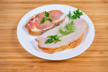Open sandwiches with cooked smoked and cured pork on dish