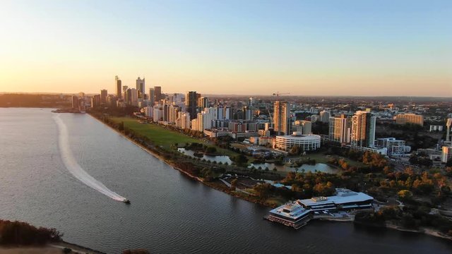 Beautiful evening aerial drone footage of the city of Perth, Western Australia, right before sunset. Speed boad on the river in the foreground and Langley park behind. Perth is the capital city of WA.