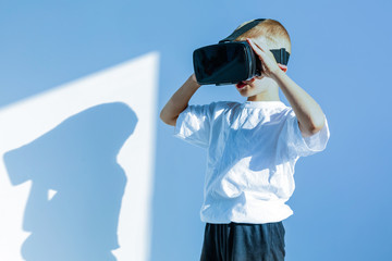 Amazed little boy looking in a VR goggles and gesturing with his hands isolated on white background