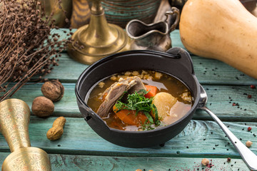 Shurpa soup with lamb in metal pot on blue wooden table