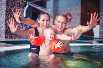 Naklejka premium happy family relaxing in the spa center with a child swims in the pool