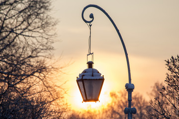Street lamp in the winter in the halo of the setting sun