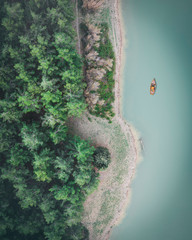 aerial view of a blue lake near a forest with a wooden boat
