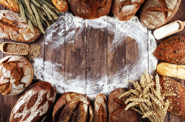 Different kinds of bread and bread rolls on board from above. Kitchen or bakery