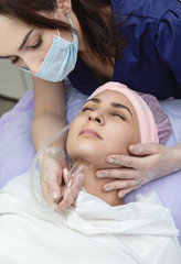 Obraz na płótnie Canvas Beautician conducts vacuum massage of skin of face of young woman in beauty salon. Cosmetology and professional skin care.