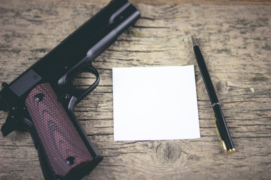 a gun and a note on a wooden table