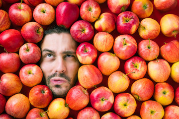 Mann mit roten Äpfeln, Konzept für die Lebensmittelindustrie. Gesicht des verziehenden Mannes im Apfelbereich