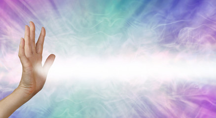 Pranic healer beaming energy to where it is needed -  female right hand facing out with a beam of white energy streaming out against a blue pink energy field background with copy space