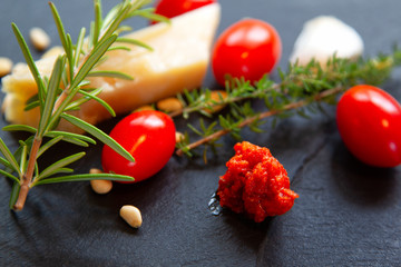 Home made Pesto Rosso with ingredients on black slate.