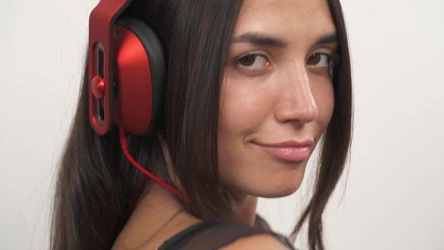A close-up of a sexy girl listening to music, smiling and sending air kiss