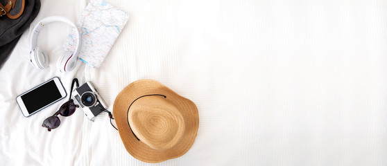 Summer travel items on blanket on bed.Top view of accessories travel (camera,hat,headphone,map ) on...