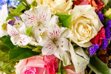 Close up photo from above of romantic bouquet of pink roses, lilies, green leaves.