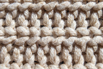 Close-up knit stitching beige close-up, handmade woolen fabric.