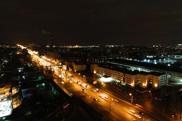Fototapeta na wymiar Aerial view of the night city. A wide motor road runs through the city block