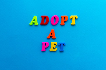 text adopt a pet from plastic colored letters on blue paper background