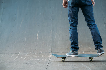 Urban skater. Leisure and lifestyle. Man on skateboard. Guy in jeans backview. Cropped shot. Skate park ramp. Copy space.