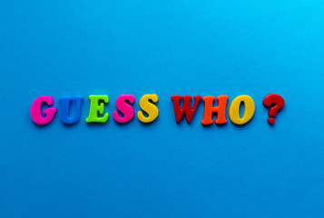 text guess who? from plastic colored letters on blue paper background