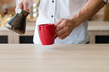 Morning coffee habit. Urban lifestyle. Man hands with jezve and red cup. Copy space.