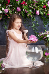 Lovely little girl playing with a bouquet of flowers in the vase