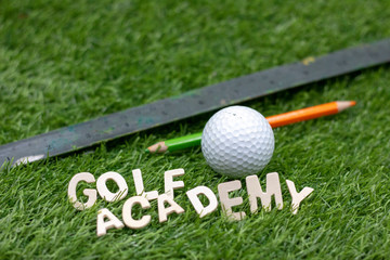 Golf Academy sign on green with golf ball and pencil 