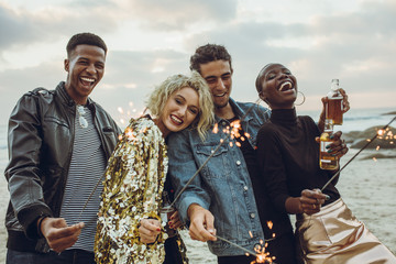 Group of friends celebrating with fireworks at beach