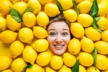 Frau mit Zitronen, Konzept für die Lebensmittelindustrie. Gesicht der lachenden Frau in der Zitronenoberfläche