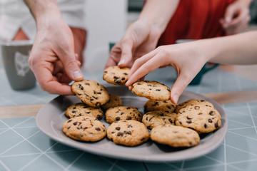 Hands take fresh cookies from plate, close-up