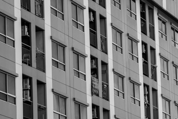 Front view of skyscraper building. Apartment building in the city. Real estate and corporate construction. Multi-storey residential building. Exterior condo in black and white scene.