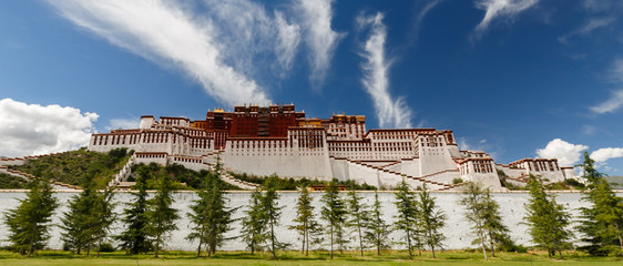 LHASA, TIBET / CHINA - July 31, 2017: Panorama of Potala Palace with trees in the foreground. Home of the Dalai Lama, an Unesco World Heritage and major tourist destination. Center of tibetan buddhism