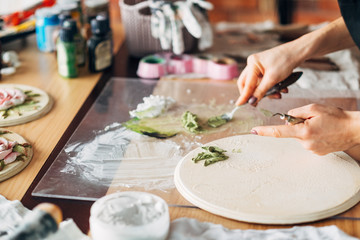 Artist at work. Studio workplace. Ceramic artwork in process. Handicraft. Woman with modeling tools in hand.