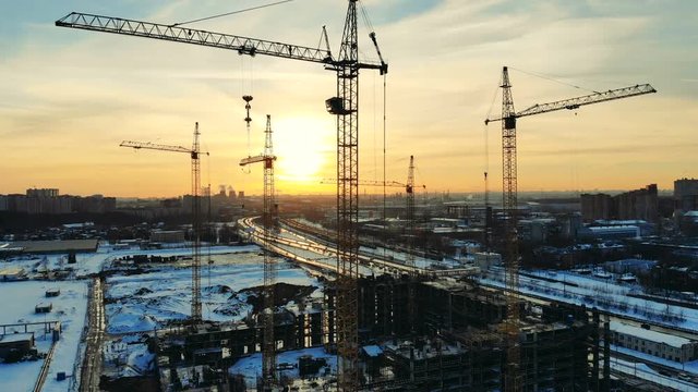Tall cranes in the construction site at the sunset