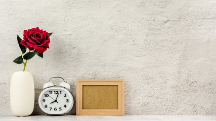 Classic wooden photo frame with alarm clock and a red rose. - blank space for message and advertising background.