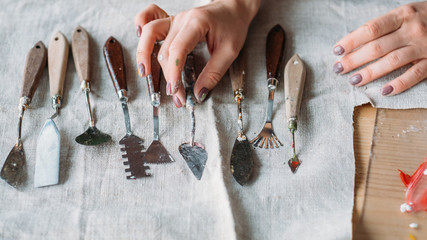 Art craft set arranged on textile. Sculpting and modeling tools. Woman hand choosing palette knife.