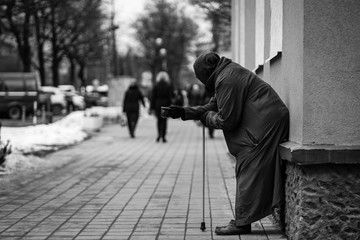 Photo of old hungry homeless female beggar beg for alms and on street.