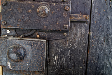 Old wooden door with metal knob and rusty medieval bolt.