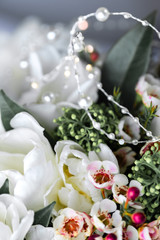 Beautiful bouquet of white tulips with green leaves and other decorative flowers close up.