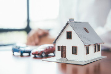 House model with real estate agent and customer discussing for contract to buy house, insurance or...