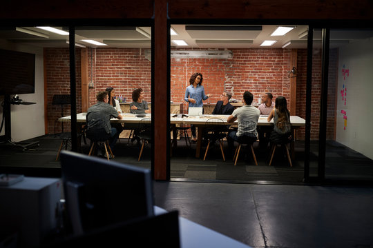 Business Team Having Late Night Meeting Sitting Around Boardroom Table