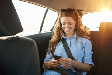 Casual woman using smartphone in car - obrazy, fototapety, plakaty