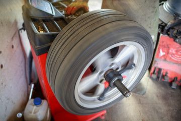 Car wheel balancing in tire service. mechanic repairman balancing automobile car wheel on balancer