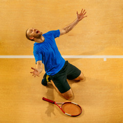 Portrait of a handsome male tennis player celebrating his success on a court background. Human...