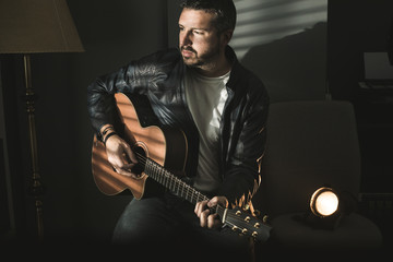 Obraz premium Dramatic portrait of a man playing a guitar. Guitarist