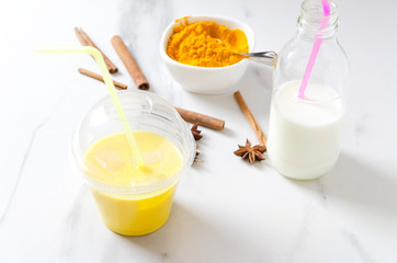 Morning healthy beverage.Preparing turmeric latte with cinnamone and star anise on marble kitchen table