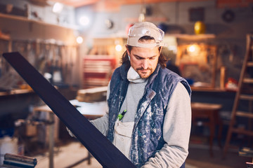 Male carpenter working on old wood in a retro vintage workshop.