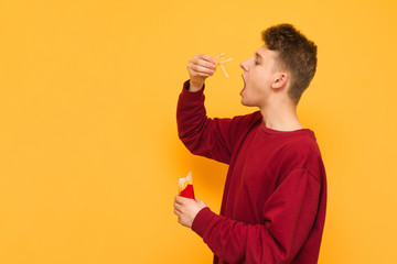 Hungry guy eating french fries on a yellow background puts potatoes in his mouth. Student and...