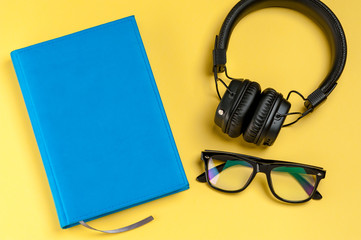 Black stylish headphones, smartphone, glasses and notebook