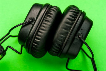 Black stylish headphones on green background.