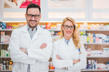 Portrait of a two beautiful young pharmacists at workplace. - obrazy, fototapety, plakaty
