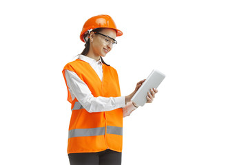 Destroying gender stereotypes. Female builder in orange helmet standing with laptop on white studio background. Safety specialist, engineer, occupation, businesswoman, job concept. Woman in the male